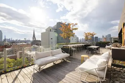 a balcony with white couches and tables on a building at Beautiful Modern Studio in Luxury Building in Brooklyn