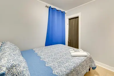 a bedroom with a bed and a blue curtain at Walk to Local Eats! Updated Schenectady Apartment in Schenectady