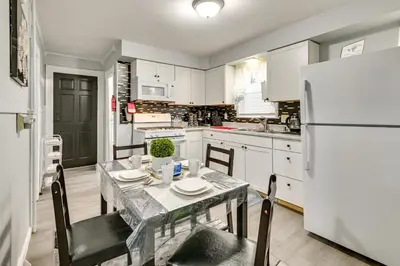 a kitchen with a table and a white refrigerator at Walk to Local Eats! Updated Schenectady Apartment in Schenectady
