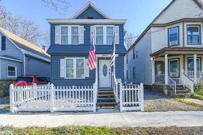 a blue house with a white fence and an american flag at Walk to Local Eats! Updated Schenectady Apartment in Schenectady