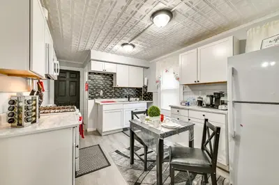 a kitchen with white cabinets and a table with chairs at 2 Mi to Union College! Newly Renovated Apartment in Schenectady