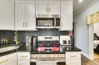 a kitchen with white cabinets and a stove top oven at Walk to Park Modern Apt 2 Mi to Union College! in Schenectady