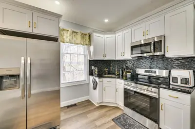 a kitchen with white cabinets and stainless steel appliances at 2 Mi to Downtown Charming Apt in Schenectady! in Schenectady