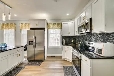 a kitchen with white cabinets and a stainless steel refrigerator at 2 Mi to Downtown Charming Apt in Schenectady! in Schenectady