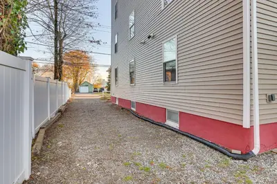a house with a red and white wall next to a driveway at 6 Mi to Dtwn New Haven Duplex with Shared Yard in West Haven