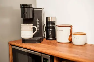 a coffee maker and cups on a wooden table at The A-Frame on Pudding Hill in Stamford