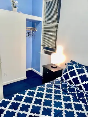 a bedroom with a bed with a blue and white comforter at 3 Bedrooms Huge Apt in LIC, very next to Manhattan in Roosevelt Island