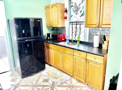 a kitchen with wooden cabinets and a black refrigerator at 3 Bedrooms Huge Apt in LIC, very next to Manhattan in Roosevelt Island