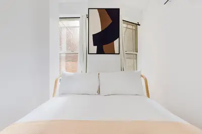 a white bedroom with a bed in front of a window at Blueground Midtown East view nr UN Plaza NYC-2126 in New York