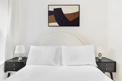 a white bedroom with a white bed with two night stands at Blueground Midtown East view nr UN Plaza NYC-2126 in New York