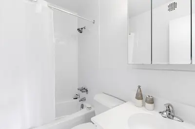 a white bathroom with a sink and a mirror at Chelsea 1BR w Water views Doorman NYC-210 in New York
