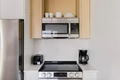 a kitchen with a stove and a microwave at Blueground Long Island City fitness center nr Gantry Plaza State Park NYC-2181 in New York