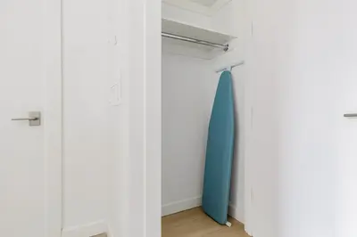 a closet with white walls and a blue surfboard at Blueground Long Island City fitness center nr Gantry Plaza State Park NYC-2181 in New York