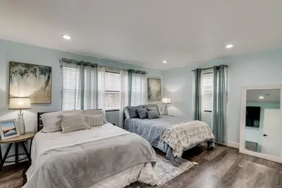 a bedroom with two beds and a desk and windows at 4 Mi to MetLife Stadium Modern Retreat! in Wallington