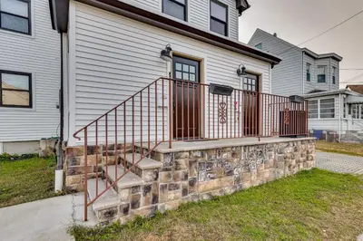 a brick retaining wall with a staircase in front of a house at 4 Mi to MetLife Stadium Modern Retreat! in Wallington