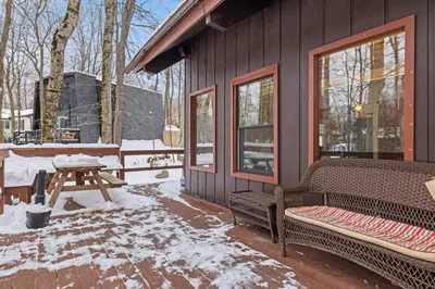 a house with a bench and a picnic table in the snow at Hot Tub + Fire Pit • Game Room • Community Pool in Tobyhanna