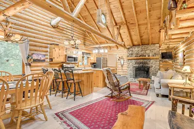 a log cabin kitchen and living room with a fireplace at On-Site Pond and Trails Lake Luzerne Cabin in Lake Luzerne