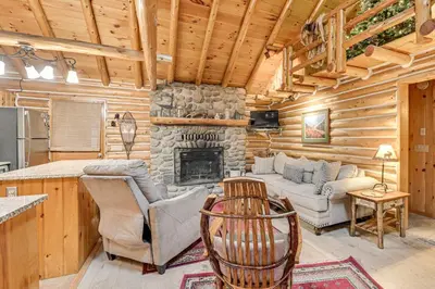 a living room with a fireplace in a log cabin at On-Site Pond and Trails Lake Luzerne Cabin in Lake Luzerne