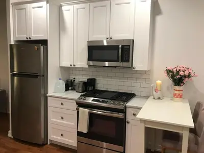 a kitchen with white cabinets and a stove and a microwave at Cosy apartment in prime West Village in New York