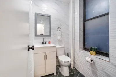 a white bathroom with a toilet and a sink at The Black Bellvue NYC in New York