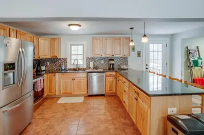 a kitchen with wooden cabinets and a stainless steel refrigerator at 5 Mi to Mt Snow Secluded Family Home with Game Area in West Dover