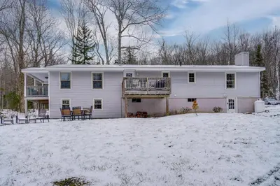 a white house with a deck in the snow at 5 Mi to Mt Snow Secluded Family Home with Game Area in West Dover