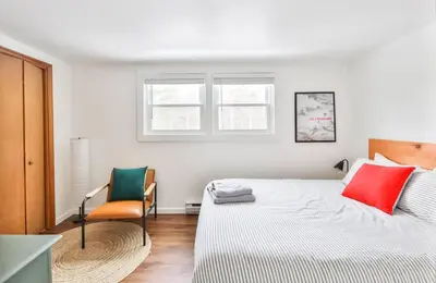 a white bedroom with a bed and a chair at Cozy Winter Retreat Minutes from Hunter Mountain in Jewett