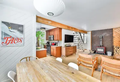 a kitchen and living room with a wooden table and chairs at Cozy Winter Retreat Minutes from Hunter Mountain in Jewett