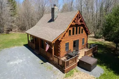 a log cabin with an american flag on it at Cozy Log Cabin with Hot Tub 10 Min to Hunter Mtn in Jewett