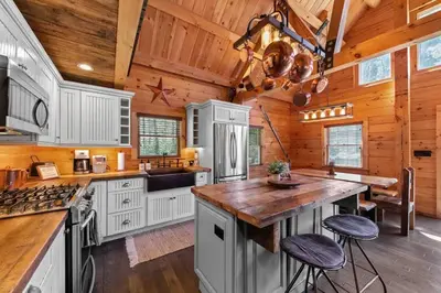 a kitchen with white cabinets and a wooden ceiling at Cozy Log Cabin with Hot Tub 10 Min to Hunter Mtn in Jewett