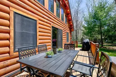 a wooden table on the porch of a house at Cozy Log Cabin with Hot Tub 10 Min to Hunter Mtn in Jewett