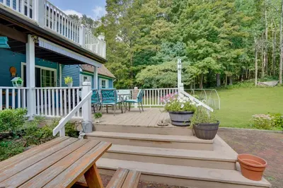a wooden deck with a bench and flowers on a house at Cozy Pittsfield Gem with Deck, Gazebo and Fireplace in Pittsfield