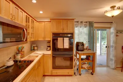 a kitchen with wooden cabinets and a stove top oven at Cozy Pittsfield Gem with Deck, Gazebo and Fireplace in Pittsfield