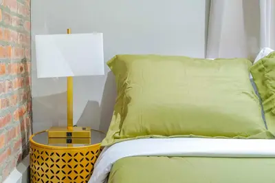 a bed with a green pillow and a lamp on a side table at New2 York Stylish 2BR Apartment in Manhattan in New York
