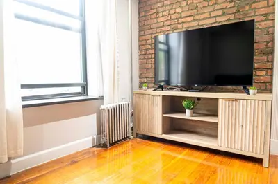 a living room with a television and a brick wall at New2 York Stylish 2BR Apartment in Manhattan in New York