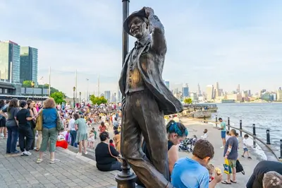 a statue of a man standing next to a crowd of people at Family-Friendly 2BR, NYC Access in Minutes in Hoboken