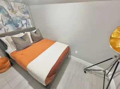 a bedroom with a bed with an orange blanket and pillows at Large 4 Bedroom NYC Property in Mott Haven