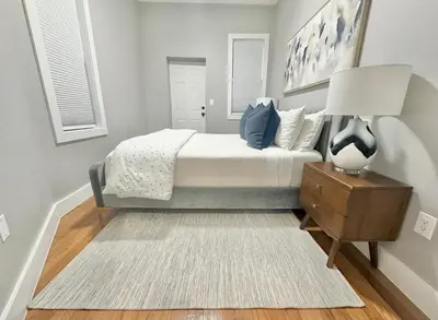 a bedroom with a bed with a lamp and a rug at Large 4 Bedroom NYC Property in Mott Haven