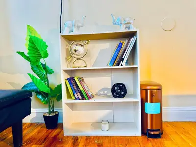a white book shelf with a clock and books at Modern Luxury Executive Room with NYC Fast Access in Paterson