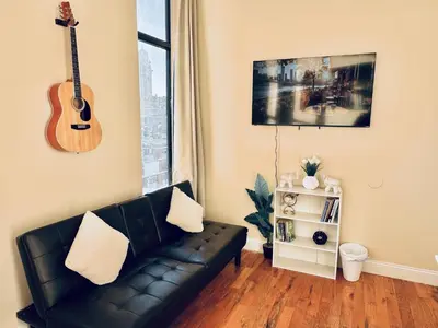 a living room with a couch and a guitar on the wall at Modern Luxury Executive Room with NYC Fast Access in Paterson