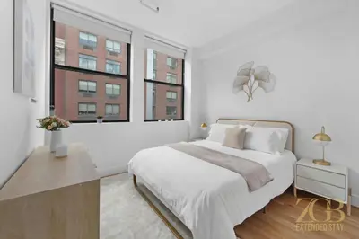 a white bedroom with a large bed and two windows at 517 - 47C Beautifully Renovated 1 bedroom in Prime Manhattan in New York