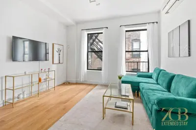 a living room with a green couch and two windows at 517 -41D Gorgeous and Fully Equipped Luxury 1 Bedroom Apt in New York