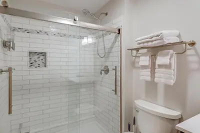 a white bathroom with a shower and a toilet at 8 Mi to Saratoga Race Course Quiet Family Home in Saratoga Springs