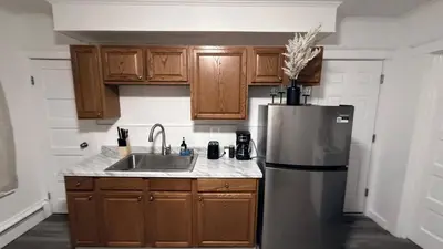 a kitchen with wooden cabinets and a stainless steel refrigerator at Nona - Private Room 2 with Parking, Desk & Fast WiFi near Yale, Quinnipiac, SCSU & Hospitals in Hamden