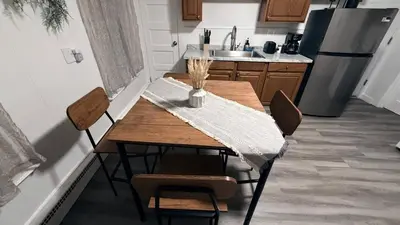 a kitchen with a wooden table with chairs and a refrigerator at Nona - Private Room 2 with Parking, Desk & Fast WiFi near Yale, Quinnipiac, SCSU & Hospitals in Hamden