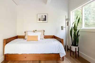 a bedroom with a bed with white sheets and a plant at Modern A-Frame Cabin with Loft, Firepit and Grill in Catskill