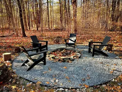 three chairs sitting around a fire in the woods at Modern A-Frame Cabin with Loft, Firepit and Grill in Catskill