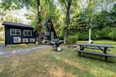 a picnic table in front of a tiny house at Modern A-Frame Cabin with Loft, Firepit and Grill in Catskill