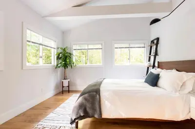 a bedroom with a bed with white walls and windows at Modern A-Frame Cabin with Loft, Firepit and Grill in Catskill