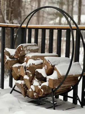 a pile of logs on a bench covered in snow at Modern A-Frame Cabin with Loft, Firepit and Grill in Catskill